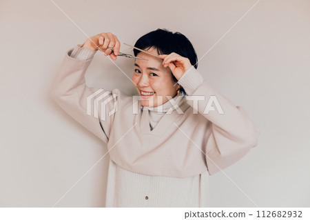 Stylish woman with a short haircut doing her own haircut 112682932