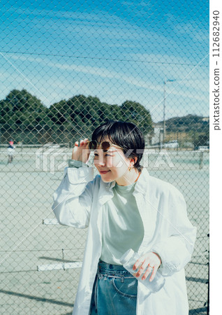 Stylish woman with a short cut hydrating outside 112682940