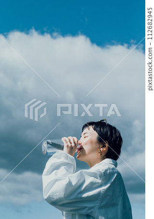 Stylish woman with a short cut hydrating outside 112682945