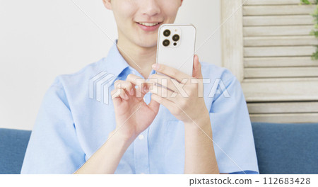 Young man using smartphone in living room, faceless Young man using smartphone in living room, faceless 112683428