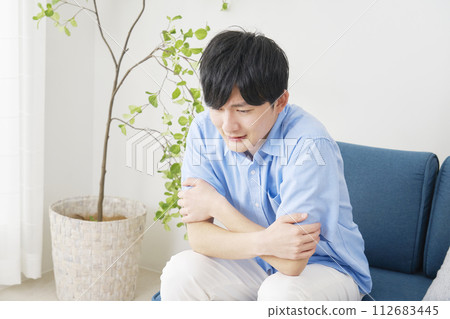 A young man feeling cold in the living room 112683445
