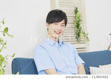 Portrait of a young man in the living room, looking at camera Portrait of a young man in the living room, looking at camera 112683482