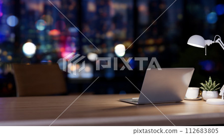 A back view image of a modern office desk in a modern skyscraper office at night by the window. A back view image of a modern office desk in a modern skyscraper office at night by the window. 112683805