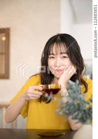 Close-up front portrait of relaxing beautiful woman drinking tea in cafe or restaurant or at home looking at camera 112683851
