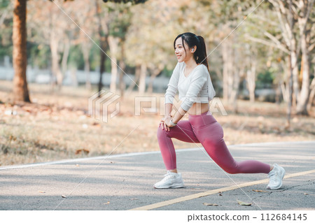 Active young woman stretching during an outdoor workout session in a park, showcasing a healthy lifestyle and fitness routine. Active young woman stretching during an outdoor workout session in a park, showcasing a healthy lifestyle and fitness routine. 112684145
