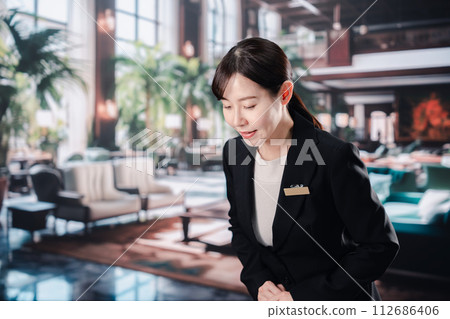 A female hotel staff member greets customers with a smile 112686406