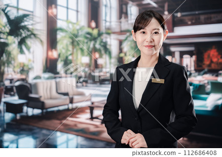 A female hotel staff member greets customers with a smile 112686408