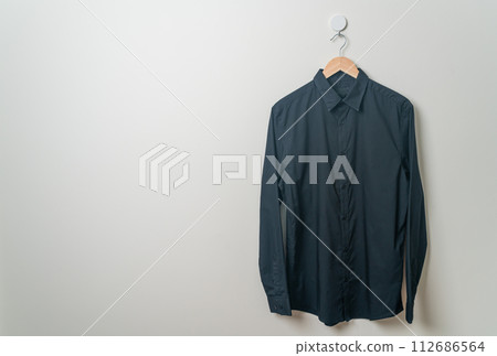 hanging shirt with wood hanger on wall 112686564
