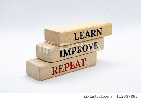 Learn, Improve and Repeat text on wooden blocks with white cover background. Improvement and development concept 112687865