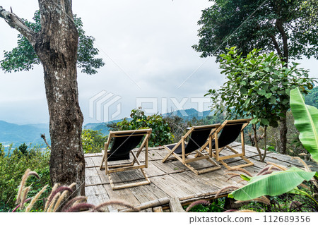 chair on balcony with mountain hill and foggy background chair on balcony with mountain hill and foggy background 112689356
