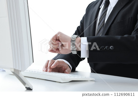 Businessman checking the time during desk work Businessman checking the time during desk work 112690611
