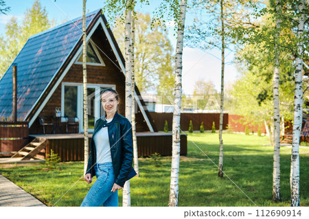 Portrait of cheerful woman in front of a-frame cabin Portrait of cheerful woman in front of a-frame cabin 112690914