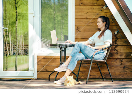 Relaxed woman sitting with laptop on terrace in a sunny day 112690924