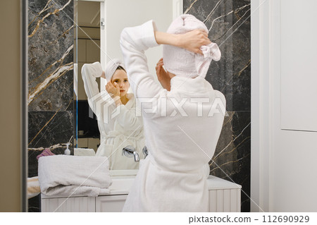 Woman in bathrobe in front of a mirror Woman in bathrobe in front of a mirror 112690929