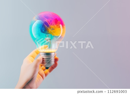 Creative hand holds a light bulb, sparking colorful ideas 112691003