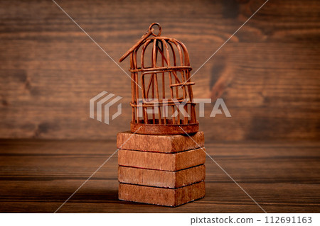 Rusty bird cage on wood texture background. Captivity, prison and the concept of repression 112691163