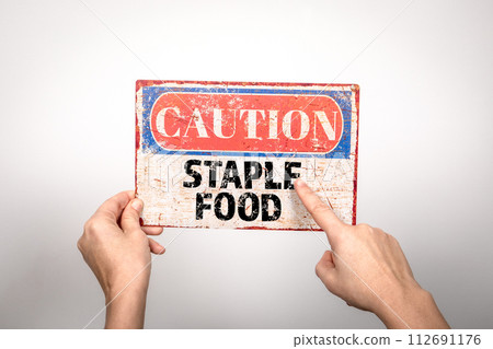 Staple Food. Metal warning sign in a woman's hand on a white background 112691176
