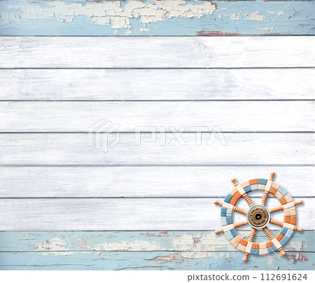 Vintage travel backdrop with little souvenir ship's helm on wood boards of white and blue color.  Horizontal retro background with old wooden planks and tiny toy steering wheel. Copy space for text 112691624