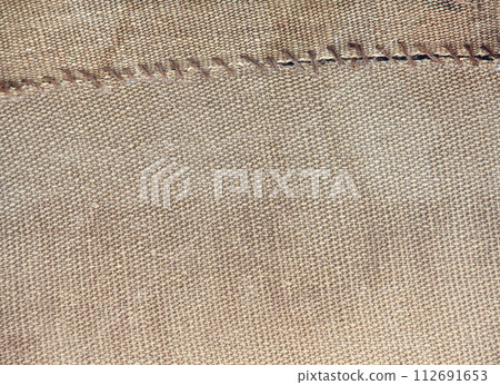 Two pieces of old burlap sewn together with thread. Horizontal background with rustic bag texture 112691653