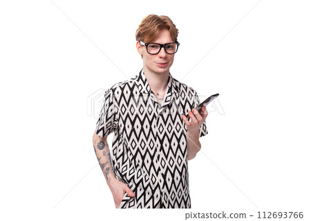 a young european guy with red hair wears glasses for vision correction and holds a phone in his hand a young european guy with red hair wears glasses for vision correction and holds a phone in his hand 112693766