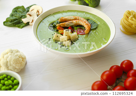 Seafood soup with spinach and croutons, mushrooms. Decorated with shrimps. 112695324
