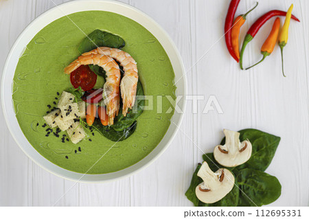 Seafood soup with spinach and croutons, mushrooms. Decorated with shrimps. Seafood soup with spinach and croutons, mushrooms. Decorated with shrimps. 112695331