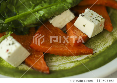 Salad of pumpkin, spinach, feta cheese and cherry tomatoes. Topped with sauce. Keto diet. 112695368
