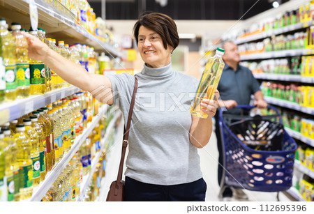 Woman chooses oil in supermarket 112695396