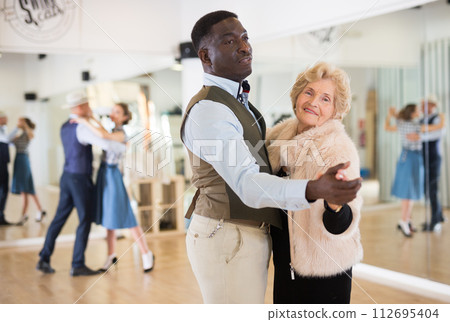 Man and mature woman learning to dance classical ballroom dance Man and mature woman learning to dance classical ballroom dance 112695404