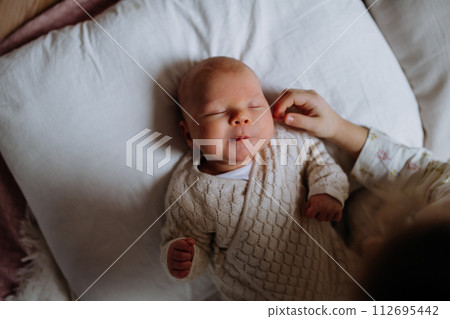 Top view of cute little baby sleeping in bed, big sister stroking newborn cheek. Sisterly love, joy for new family member. Top view of cute little baby sleeping in bed, big sister stroking newborn cheek. Sisterly love, joy for new family member. 112695442