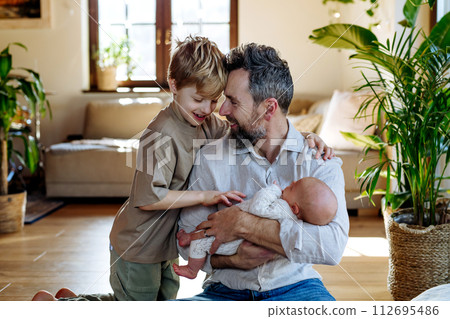 Father and boy holding newborn baby. New sibling. Unconditional paternal love, Father's Day concept. 112695486