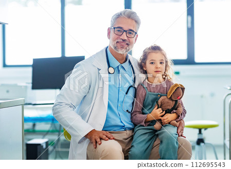 Portrait of a pediatrician with a little patient sitting on his knee. Friendly relationship between the doctor and child patient. 112695543
