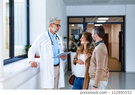Pregnant woman and husband talking to obstetrician in hospital. Admitting woman in labor to maternity ward, planned cesarean section delivery. 112695552