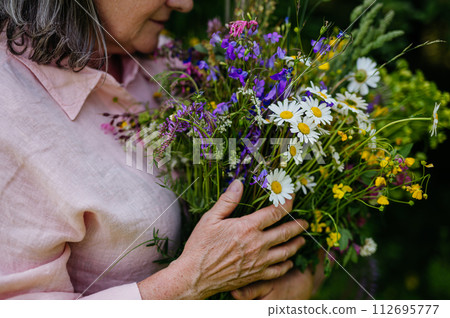 Woman holding beautiful bouquet from meadow flowers. A colorful variety of summer wildflowers. 112695777