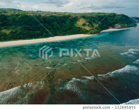 Scenic beach with cliffs and ocean on Bali. Aerial view of vacation coastline Scenic beach with cliffs and ocean on Bali. Aerial view of vacation coastline 112695855