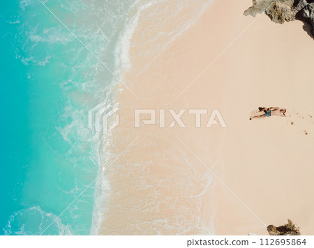 Man sunbathing at tropical ocean beach. Aerial view 112695864