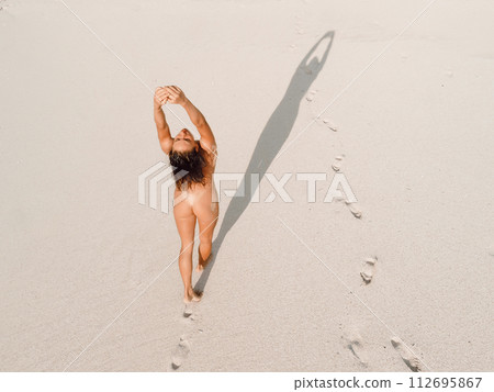 Naked woman relaxing and sunbathing on beach near the ocean. 112695867