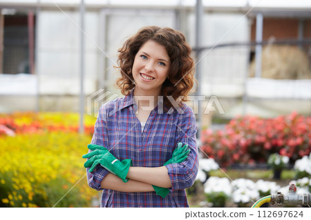 happy female nursery worker trimming plants in greenhouse happy female nursery worker trimming plants in greenhouse 112697624