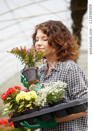 happy female nursery worker trimming plants in greenhouse 112698009