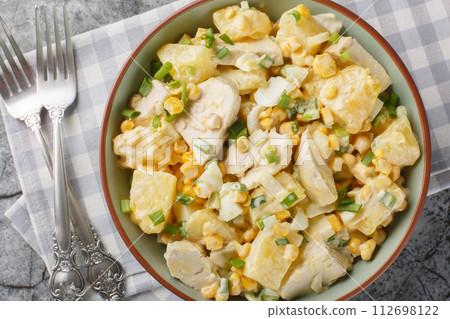 Festive Chicken salad with fresh pineapple, corn, cheese, eggs and onions dressed with mayonnaise close-up in a plate. Horizontal top view 112698122