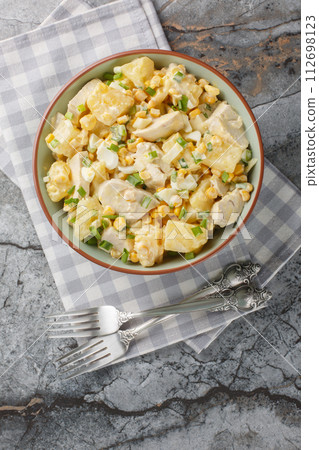 Chicken salad with pineapple, corn, cheese, eggs and onions dressed with mayonnaise close-up in a plate. Vertical top view Chicken salad with pineapple, corn, cheese, eggs and onions dressed with mayonnaise close-up in a plate. Vertical top view 112698123