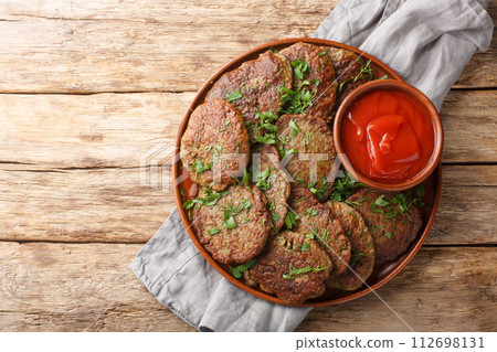 Delicious dietary liver patties served with tomato sauce and herbs close-up in a plate. Horizontal top view Delicious dietary liver patties served with tomato sauce and herbs close-up in a plate. Horizontal top view 112698131