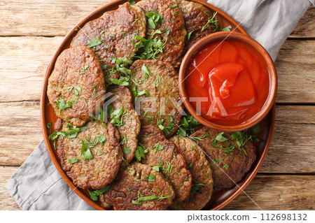 Spicy liver pancakes served with tomato sauce and herbs close-up in a plate. Horizontal top view Spicy liver pancakes served with tomato sauce and herbs close-up in a plate. Horizontal top view 112698132