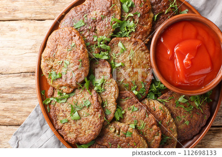 Homemade liver cutlets served with tomato sauce and herbs close-up in a plate. Horizontal top view Homemade liver cutlets served with tomato sauce and herbs close-up in a plate. Horizontal top view 112698133