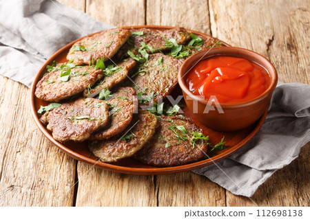 Delicious dietary liver patties served with tomato sauce and herbs close-up in a plate. Horizontal Delicious dietary liver patties served with tomato sauce and herbs close-up in a plate. Horizontal 112698138