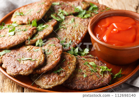 Homemade liver cutlets served with tomato sauce and herbs close-up in a plate. Horizontal 112698140