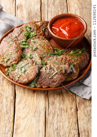 Beef liver cutlets served with tomato sauce close-up in a plate. Vertical Beef liver cutlets served with tomato sauce close-up in a plate. Vertical 112698141