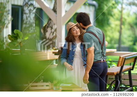 Friends meeting at a restaurant terrace. Greeting, hugging, after long time of not seeing each other. Concept of long-term friendships. Friends meeting at a restaurant terrace. Greeting, hugging, after long time of not seeing each other. Concept of long-term friendships. 112698200