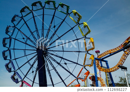 Colorful rides in motion in amusement park on sky background. 112698227