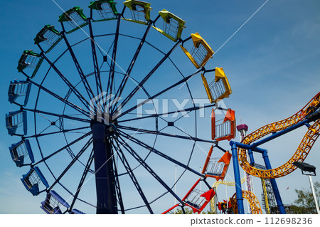 Colorful rides in motion in amusement park on sky background. Colorful rides in motion in amusement park on sky background. 112698236